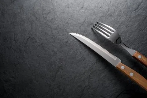 Black stone slate board with fork and knife, top view. Stock Photos