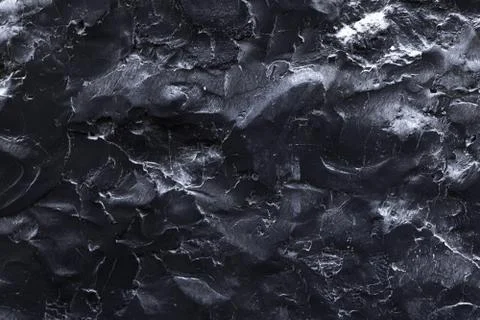 A black stone surface with an uneven texture in the form of bulges and cracks Stock Photos