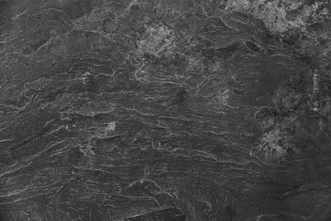 A black stone wall with a rough texture Stock Photos