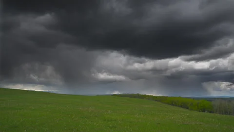 Black storm clouds over green prairie grass in foothills, 4k Stock Footage 276328996