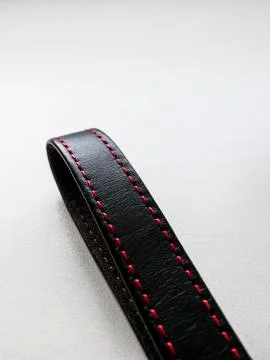 Black stripe with a red thread on a white background. Stock Photos