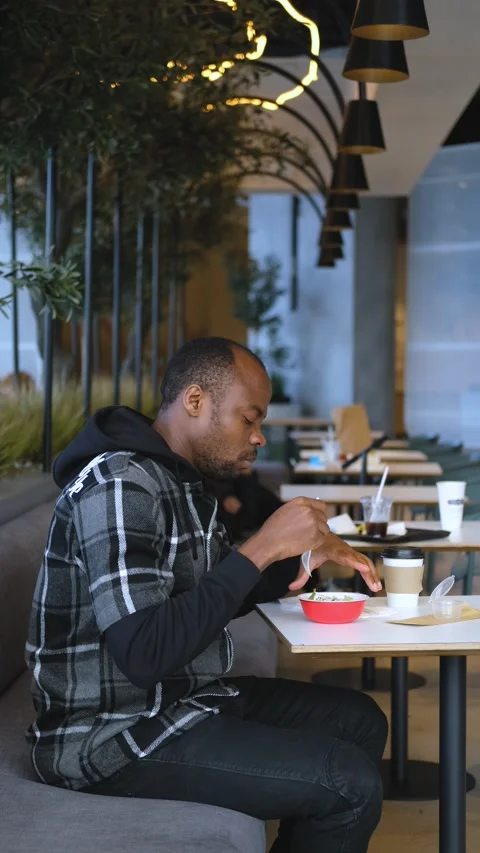 Black student eats in the cafeteria of the university, vertical video 動画素材 234552383
