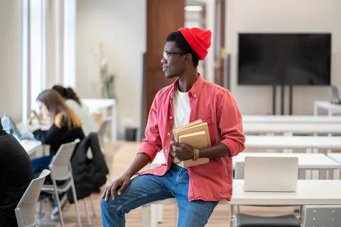 Black student guy looking out of window thinking about weekend plans while Stock Photos