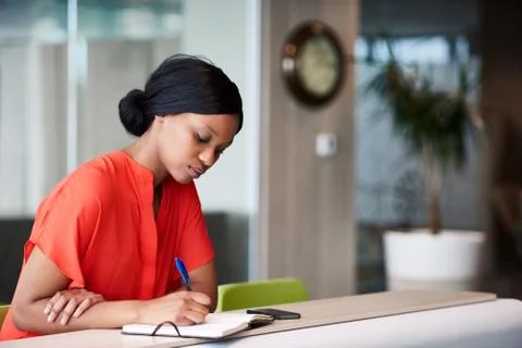 Black student making notes in her notebook sitting at home Stock Photos