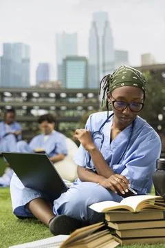 Black student reading and taking notes from book and laptop Stock Photos