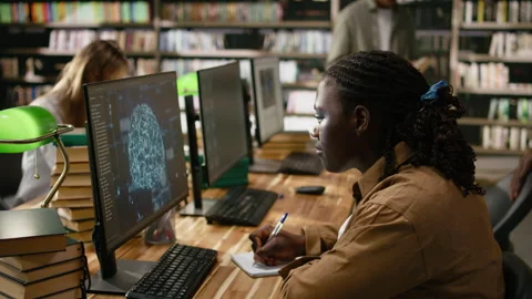 Black student working with AI brain display on desktop computer in library Stock Footage 337229014