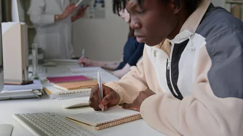 Black Student Writing in Notebook and Using Computer During Chemistry Class Video stock 312322180