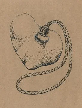 Black stylized stone amulet in the form of a heart on the beige background Stock Photos