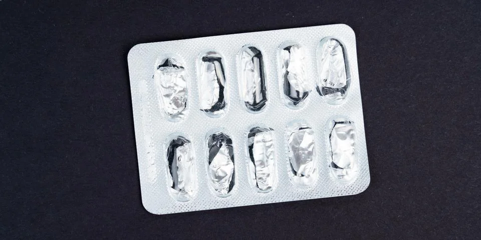 On the black surface is an empty pill pack. Stock Photos