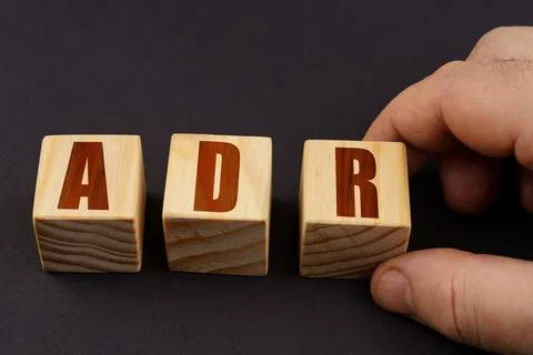 On a black surface, a man puts cubes with the inscription - ADR Stock Photos