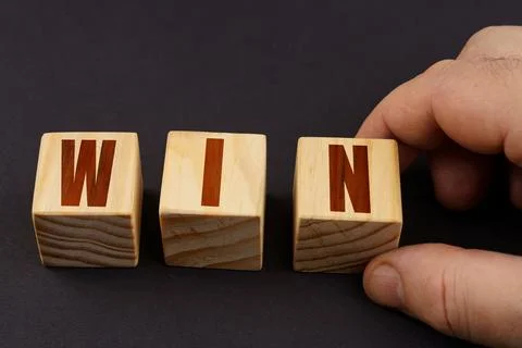 On a black surface, a man puts cubes with the inscription - WIN 스톡 사진