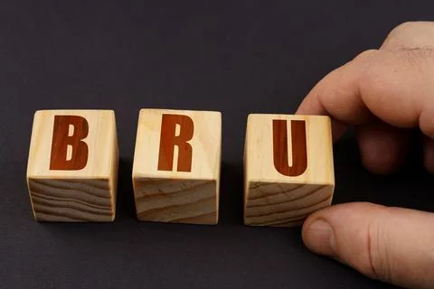 On a black surface, a man puts cubes with the inscription - BRU 库存照片