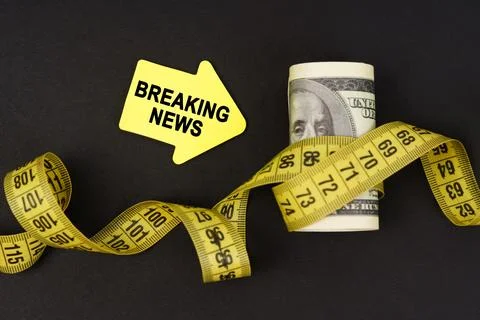 On a black surface there are dollars wrapped in measuring tape and stickers.. Stock Photos