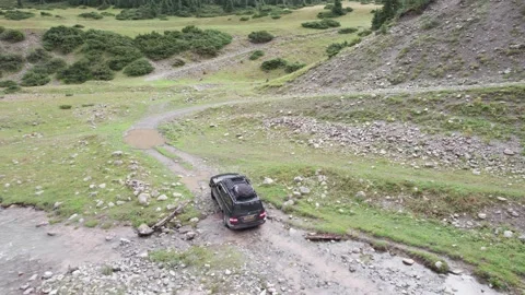 A black SUV drives through a mountain river 스톡 동영상 296282699