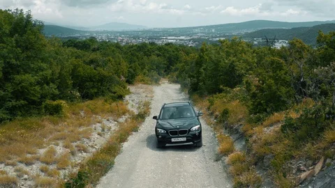 Black SUV quickly goes off-road in the forest against the backdrop of the city Stock Footage 128743424