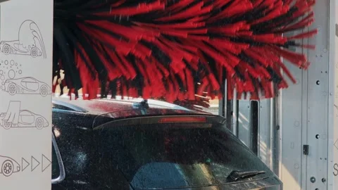 Black SUV under red brushes in automatic car wash bay Stock Footage 343794056