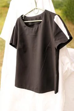 A black t-shirt on a white background hangs on a hanger. Stock Photos