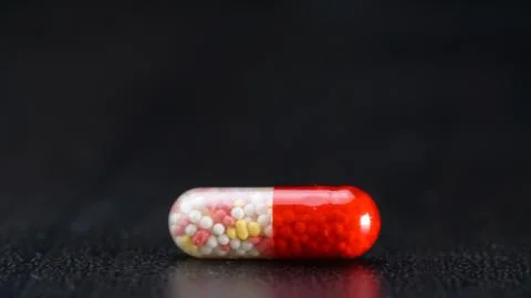 On the black table, a capsule with granules in close-up Stock Photos