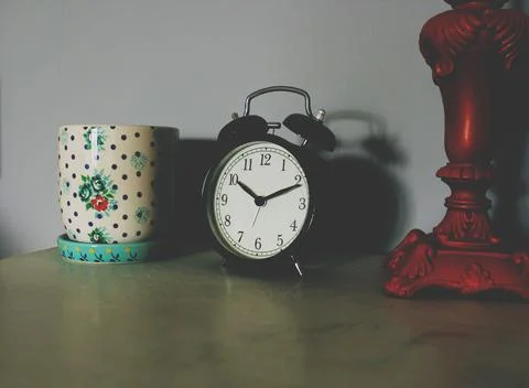 Black Table Clock Beside Ceramic Vase Stock Photos