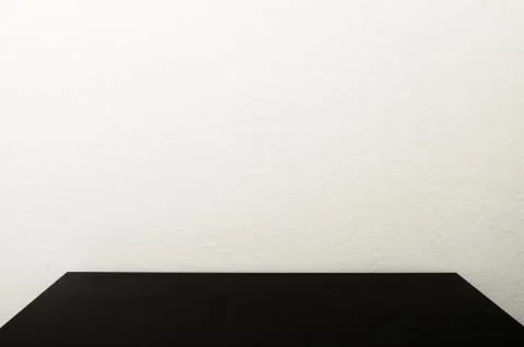 Black table in front of polished cement wall, white concrete loft style wall Stock Photos