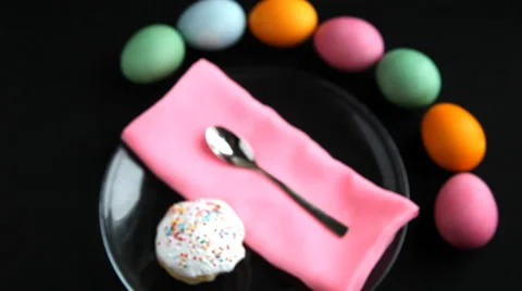 On black table lay different colored eggs, Easter cake, plate spoon, and napkin. Stock Footage 61750103