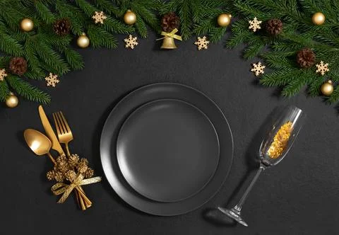 Black table setting with empty plate, gold cutlery, festive accessories  Stock Photos
