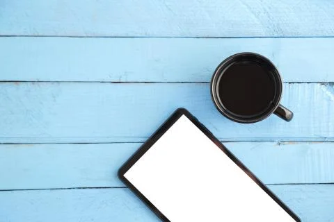 Black tablet and a Cup of drink on a blue wooden background. the view from th Stock Photos