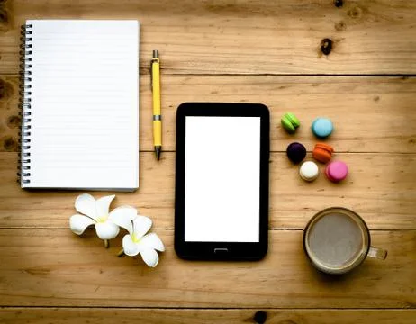 Black tablet and empty book with hot coffee and colorful sweet on  wooden tab Stock Photos