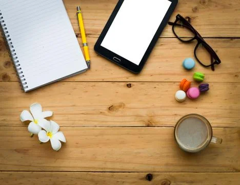 Black tablet and empty book with hot coffee and colorful sweet on  wooden tab Stock Photos