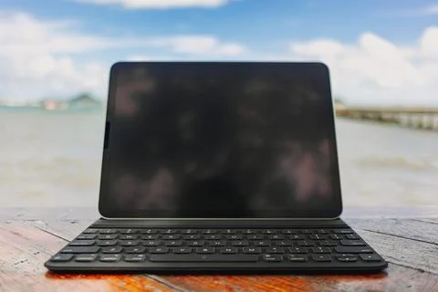 Black tablet with keyboard on table and sea view in concept of workation. Фото