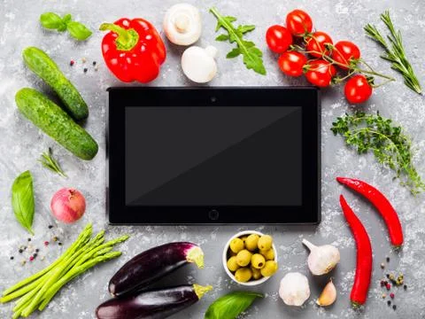Black tablet pc with vegetables and herbs on gray concrete background 스톡 사진