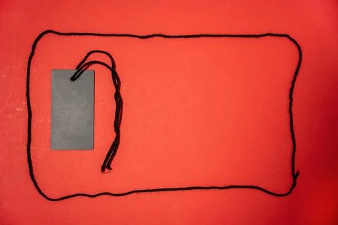Black tag with a string on a red background. 스톡 사진