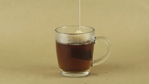 Black tea bag lifting and dropping into glass transparent mug to brew tea Stock Footage 129444401