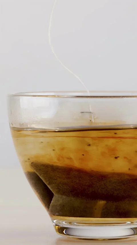 Black Tea Bag Steeping in Transparent Glass Cup Stock Footage 341924420