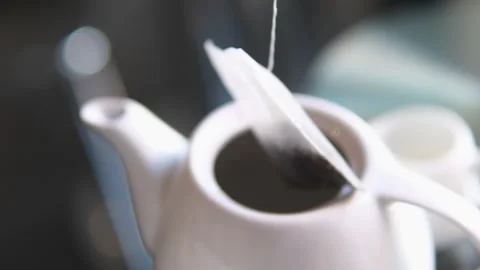 Black Tea Brewing in a White Mug. Tea Bag Comes Out Of A Cup On A Black Table In Stock Footage 301431778