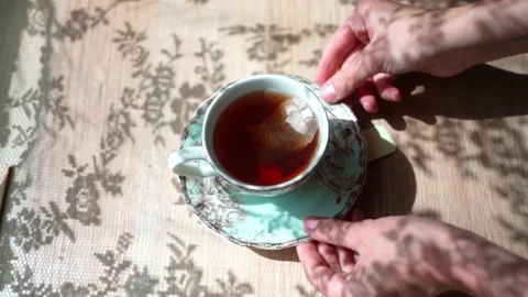 Black tea is in the cup. The tea bag is in a cup. Beautiful shadow on the table Stock Footage 133996709