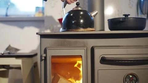 A black tea kettle sits on top of a stove Stock Footage 295370084