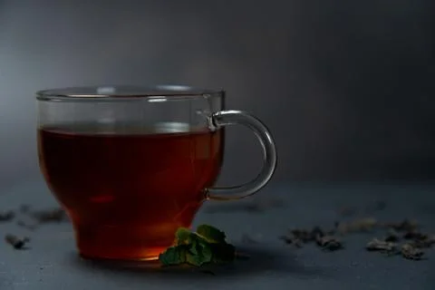 Black tea with mint and lemon in a glass cup on a dark background Stock Photos