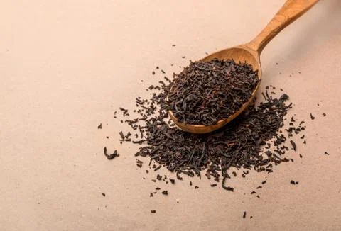 Black tea in spoon close-up on paper background Foto stock