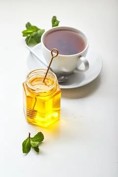 Black tea in white cup with mint leaves and honey. Calming and revitalizing t Stock Photos