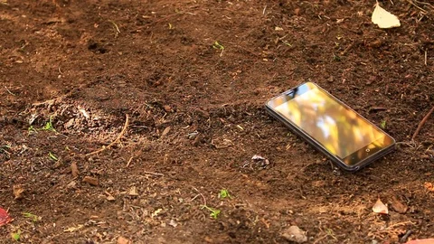 On a black telephone lying on the ground, falling autumn leaves Stock Footage 83327258