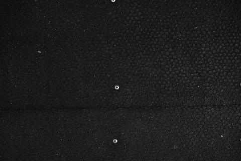 Black textured surface with small shiny metallic studs and a horizontal seam Foto stock