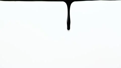 Black thick paint flows down on a white background close up. A drop forms and Video stock 156736883