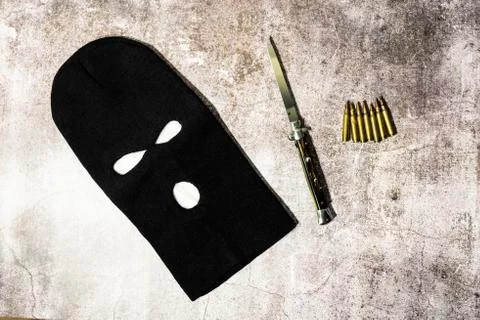 Black thieving balaclava with automatic knife and war bullets Stock Photos