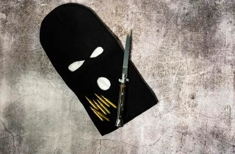 Black thieving balaclava with automatic knife and war bullets Stock Photos