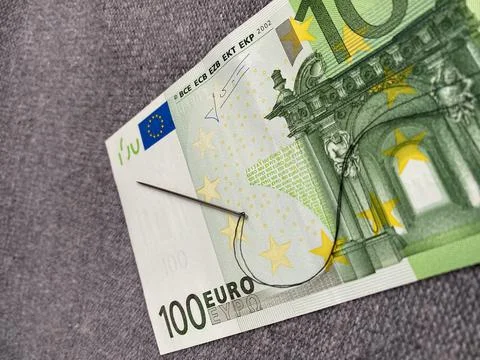 Black thread with a needle are on the 100 euro banknote. The background Stock Photos