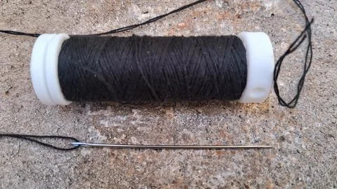Black thread spool with sewing needle. Textile equipment for tailoring and craft Stock Photos