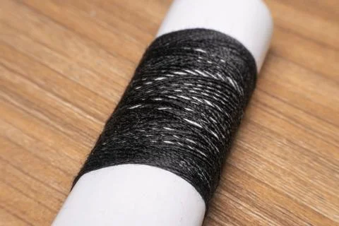 Black Thread Spool On Wooden Surface Foto stock