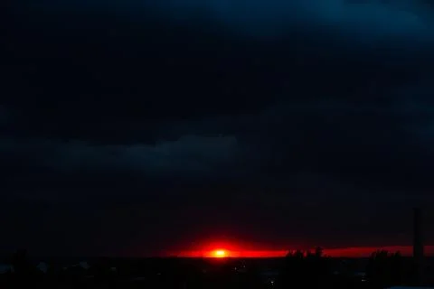 Black thunderclouds at sunset. Bright orange sunset and dark clouds. Storm sk Stock Photos