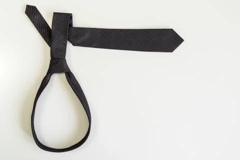 Black tie knotted in a loop shape on a white background. Stock Photos